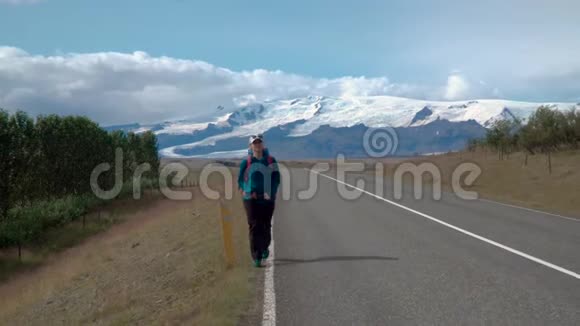 带背包的女旅行者在柏油路上视频的预览图