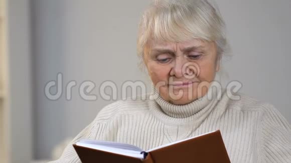 坐在轮椅上的老太太拿着书在桌子上找眼镜视频的预览图