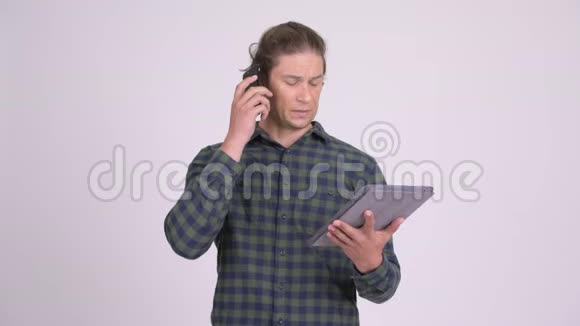 穿着时髦的男人一边用数码平板电脑一边打电话视频的预览图