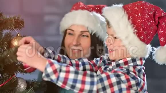 中度特写的幸福家庭微笑妈妈和可爱的宝贝儿子一起装饰圣诞树视频的预览图