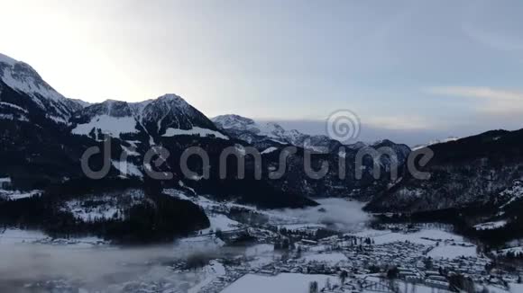 早晨在山上覆盖着白雪和树木雾在村庄上方4k视频的预览图