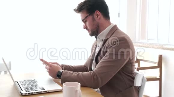 英俊的年轻商人在办公室工作时使用他的智能手机视频的预览图