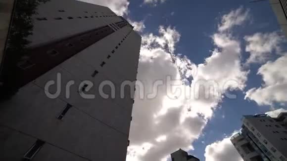 在阳光明媚的日子里在摩天大楼中间云层的时间流逝视频的预览图