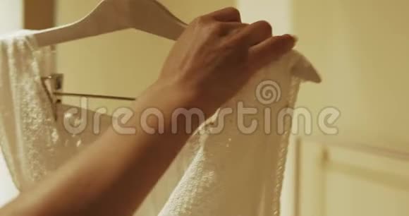 女性的手在触摸衣架上的一件新的白色睡衣视频的预览图