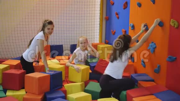 少女们在蹦床中心玩得很开心在一堆五颜六色的软立方体中视频的预览图