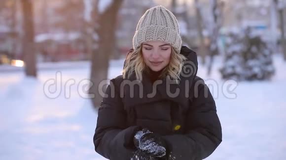 美丽的女人在冬天的公园里扔雪球慢动作视频的预览图