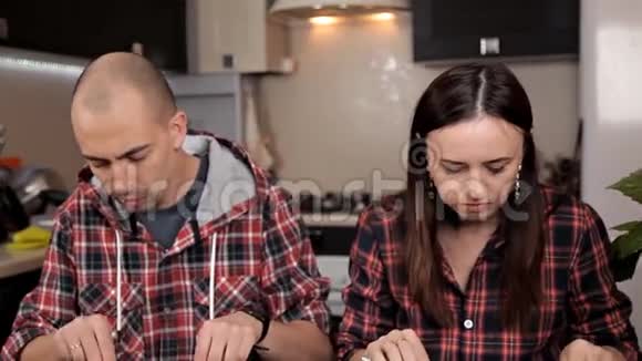 快乐的年轻夫妇穿着红色衬衫在餐桌上吃晚饭厨房房子视频的预览图