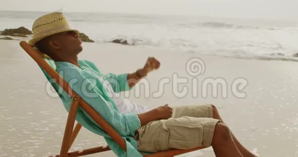 在海滩上的阳光休息室里放松的非裔美国人侧面景色视频的预览图