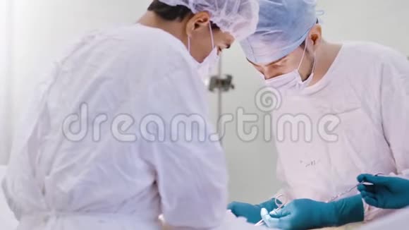 两位年轻而自信的医生戴着帽子戴着口罩同时进行低角度的统一手术视频的预览图