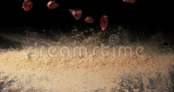 大蒜野蒜大蒜爪落在黑色背景的蒜粉上动作缓慢视频的预览图