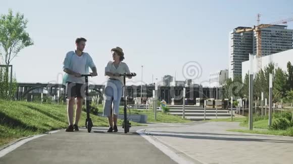 年轻夫妇带着电动滑板车在夏季公园约会视频的预览图