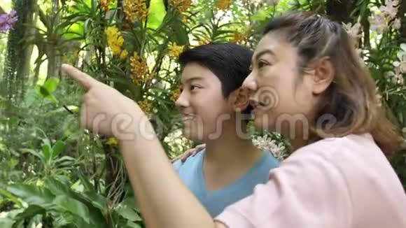 幸福的亚洲家庭母子笑着走在兰花园里视频的预览图