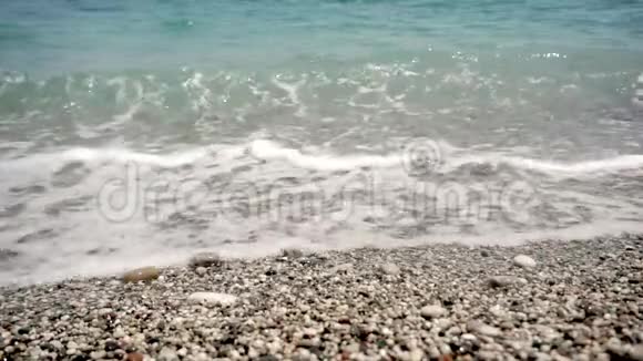 夏日海滩的景色鹅卵石覆盖着海面表面有淡淡的泡沫视频的预览图
