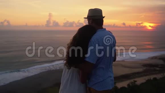 情侣拥抱看着美丽的夕阳和海洋慢动作视频的预览图