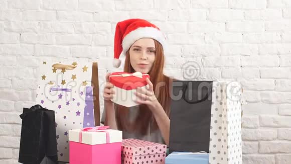 圣诞老人的帽子里戴着一个快乐红发女孩拿着一个圣诞盒子对着镜头微笑视频的预览图