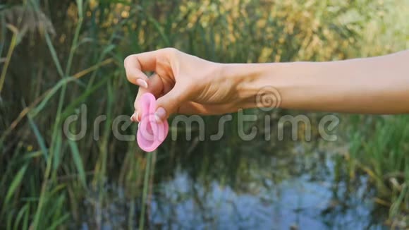 粉红色硅胶月经杯在女性手上的绿色自然背景与湖泊妇女健康观念零浪费视频的预览图