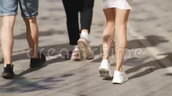 人们走在市中心的石路上穿着白色运动鞋的女孩走在人行道上视频的预览图