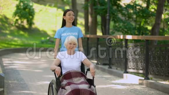 有残疾老人的幸福社会志愿者步行医院花园视频的预览图