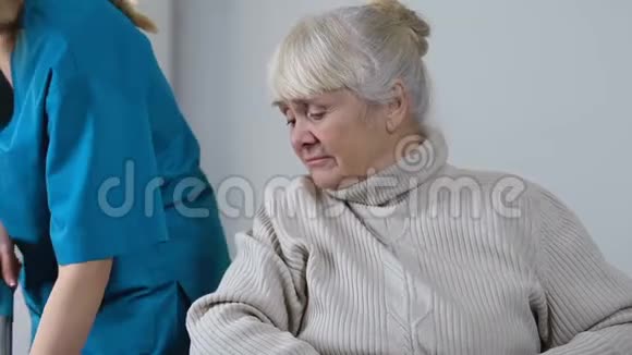 医务人员靠边挪悲伤残疾老年女性坐轮椅孤独视频的预览图