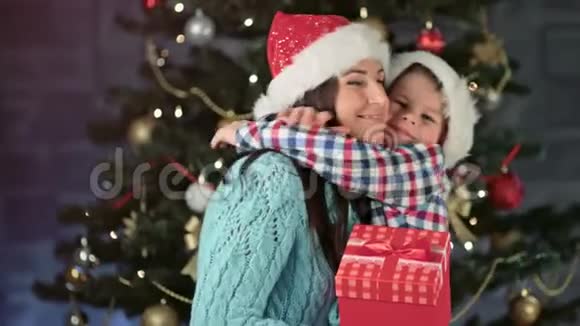 幸福的家庭微笑的妈妈和可爱的小太阳戴着圣诞老人的帽子拥抱和感情视频的预览图