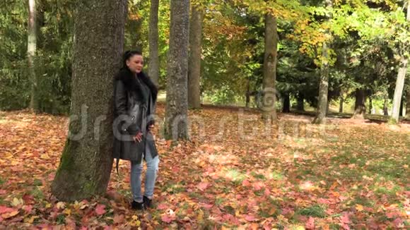 秋天公园穿黑色斗篷的漂亮女孩视频的预览图