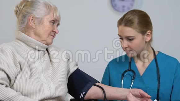 年轻护士测量残疾老年女性血压并记录视频的预览图