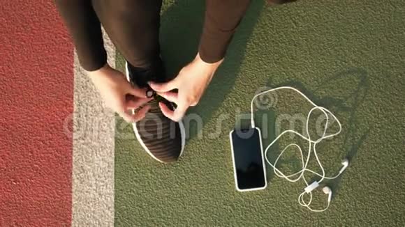 女跑步者的脚准备把运动鞋和耳机绑在地上关门视频的预览图