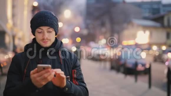 男人用智能手机在城市的夜晚行走视频的预览图