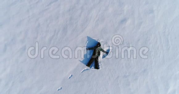七岁的男孩做雪天使空中镜头摄像机慢慢接近视频的预览图