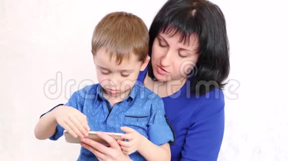 年轻的母亲和儿子正在玩智能手机在白色背景下微笑视频的预览图