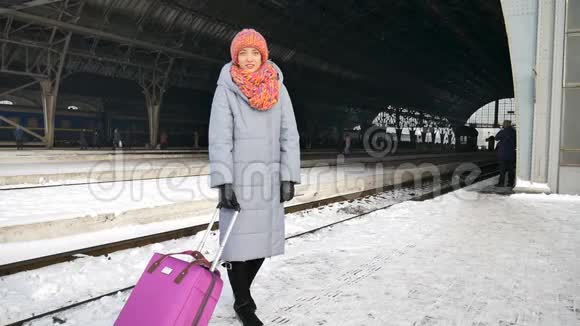 冬季火车站带紫色行李箱的年轻女孩的后景视频的预览图