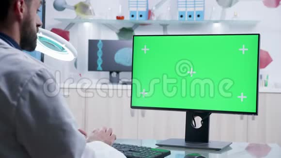 用绿色屏幕模型放大在电脑上工作的医生镜头视频的预览图