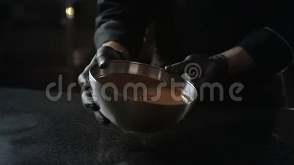 巧克力师把融化的巧克力从碗里倒入冷桌用来调质制作糖果和手工制作视频的预览图