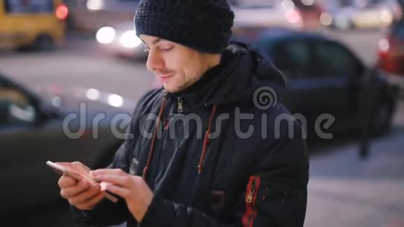 男人用智能手机在城市的夜晚行走视频的预览图