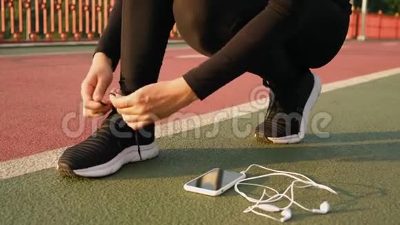 女人在城市桥上系鞋带然后再跑女运动员在日出时系跑鞋视频的预览图