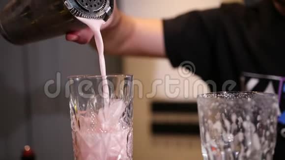 带摇床的酒保把粉红色的鸡尾酒倒入刻有冰块的杯子里视频的预览图