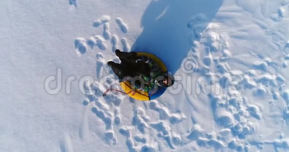 七岁的男孩正在雪地里铺设油管摄像机慢慢接近空中镜头视频的预览图