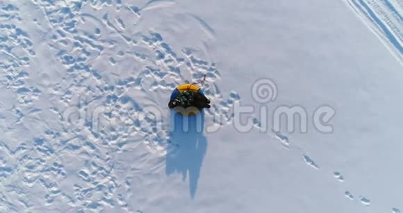 七岁的男孩正在雪地里铺设油管相机慢慢地上升和旋转空中镜头视频的预览图