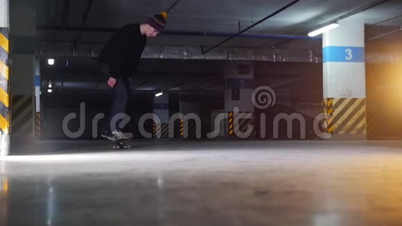 地下停车场一个年轻人在玩滑板练习复杂的技巧视频的预览图