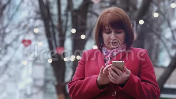 微笑的成年女性使用智能手机在公园放松背景灯视频的预览图
