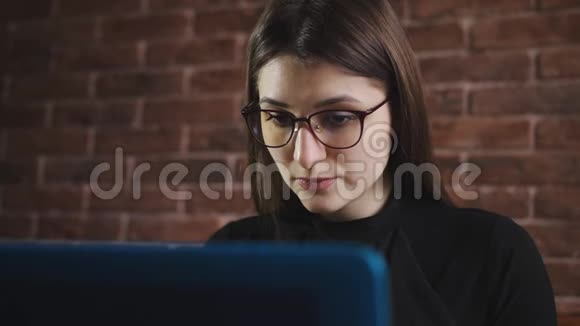 带眼镜的年轻女孩正在办公室的笔记本电脑键盘上打字年轻记者在电脑键盘上打字视频的预览图
