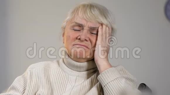 坐在轮椅上的老年女士头痛揉太阳穴桌上有药片视频的预览图