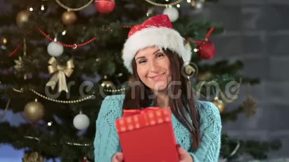 在圣诞树附近戴圣诞老人礼帽的欧洲女性微笑画像视频的预览图