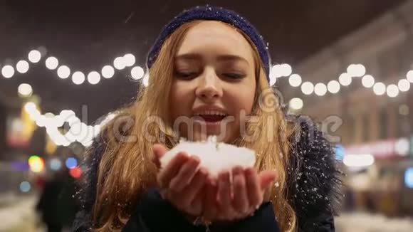年轻女子手中吹雪的肖像雪向不同方向散射视频的预览图