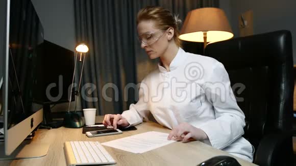 女科学家在办公室工作时通过电话阅读文件并键入信息视频的预览图