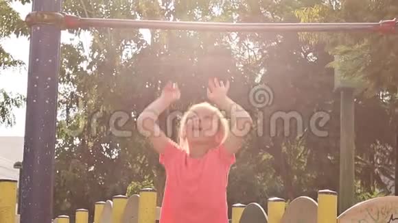 可爱的小女孩在操场上玩挂在水平杆上慢动作视频的预览图