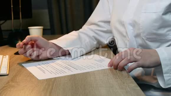 女科学家穿着白色制服坐在一张桌子旁写着一个测试把手举起来视频的预览图