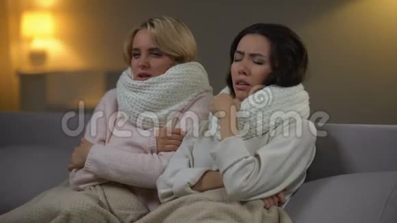 两个带围巾的生病女孩坐在床上打喷嚏流感病毒医疗保健视频的预览图