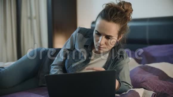 年轻女子躺在家里的沙发上手提电脑女士电脑工作视频的预览图