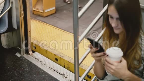 高角度相机在吸引年轻的欧洲妇女在地铁列车使用智能手机车门关闭在站台视频的预览图